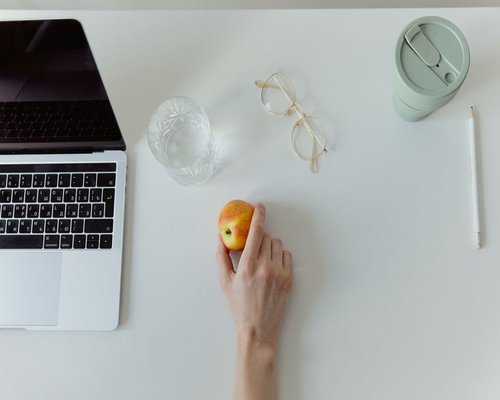 An office desk featuring dynamic workplace layout with healthy snacks like fresh fruit slices and pure mineral water